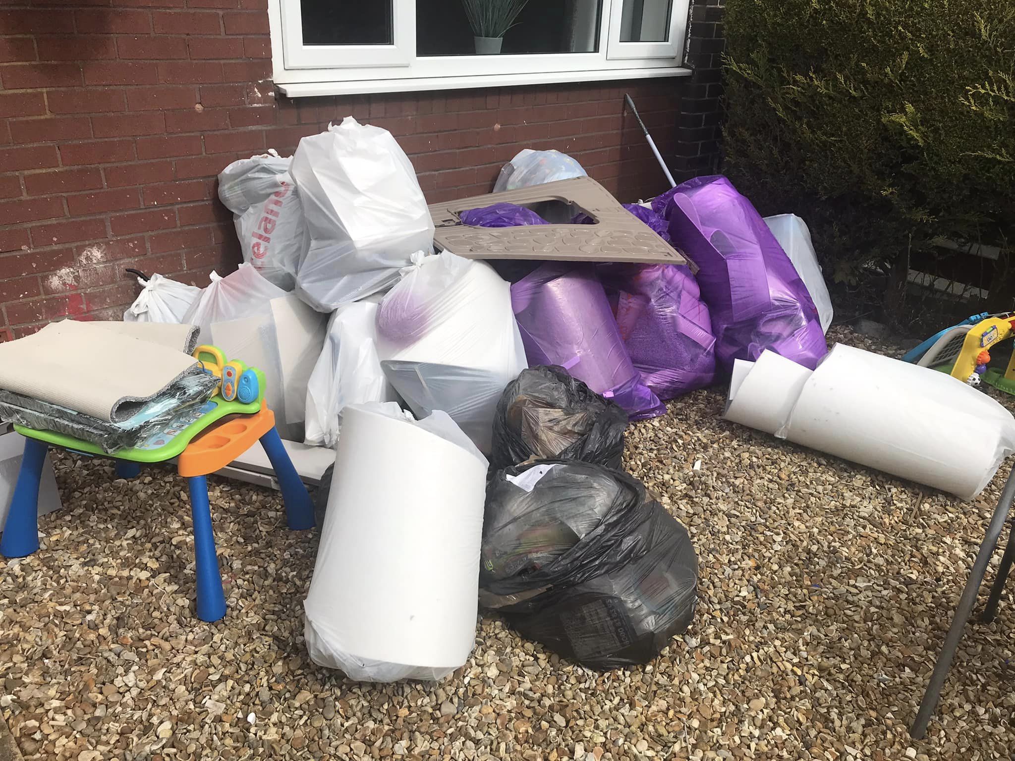 images of purple, black and white bin bags and a childrens plastic toy table outside a home waiting for waste removal